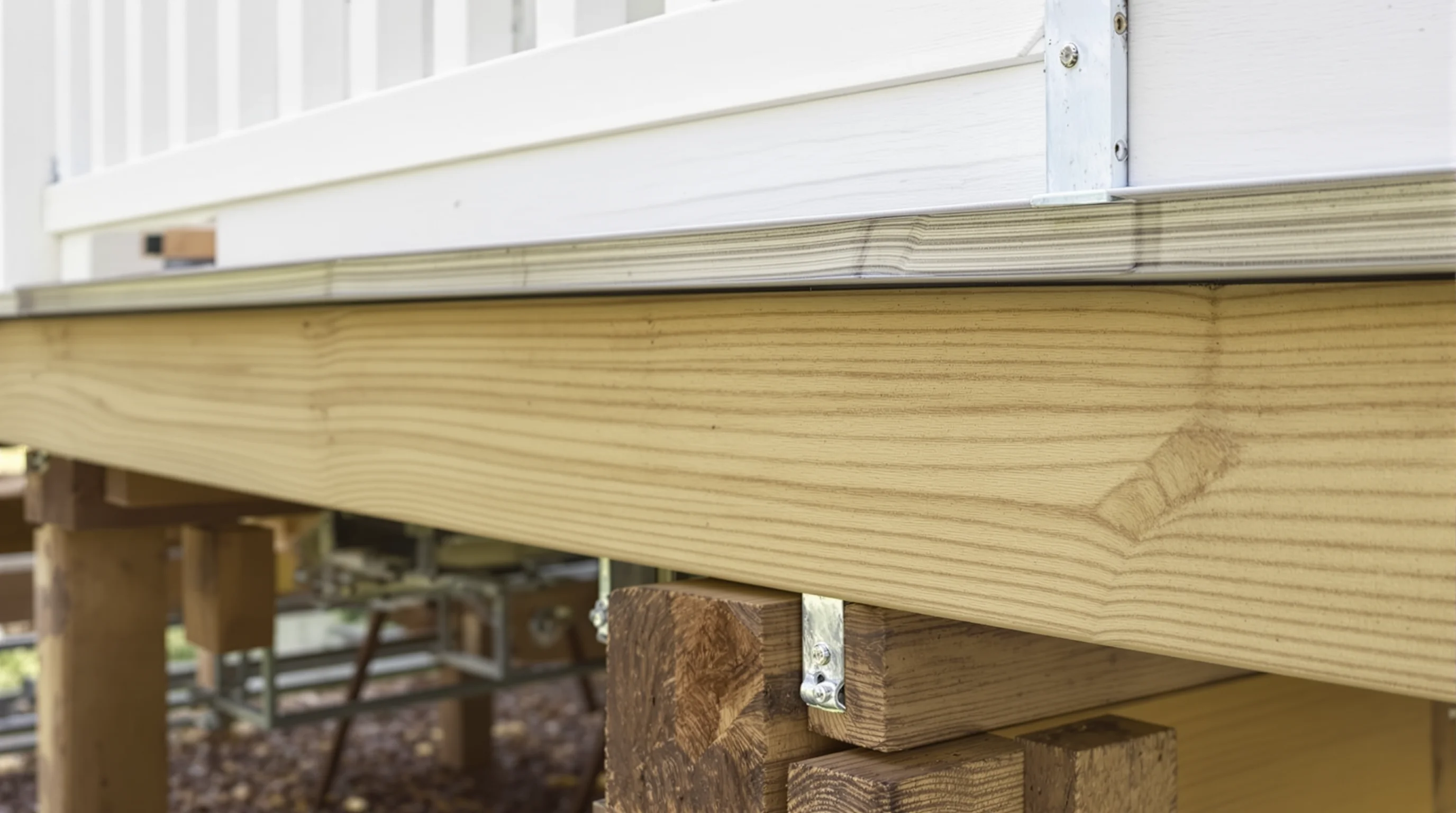 Deck framing and ledger board construction detail showing pressure-treated lumber and hardware
